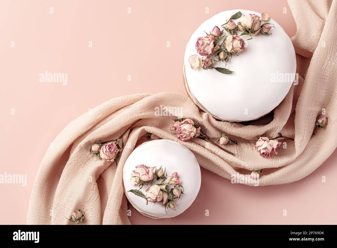 Gâteaux de Pâques émaillés décorés de fleurs de rose de thé sur fond pastel. Composition de Pâques avec gâteaux, roses et serviette. Arrière-plan de Pâques avec espace de copie pour votre conception. Banque D'Images