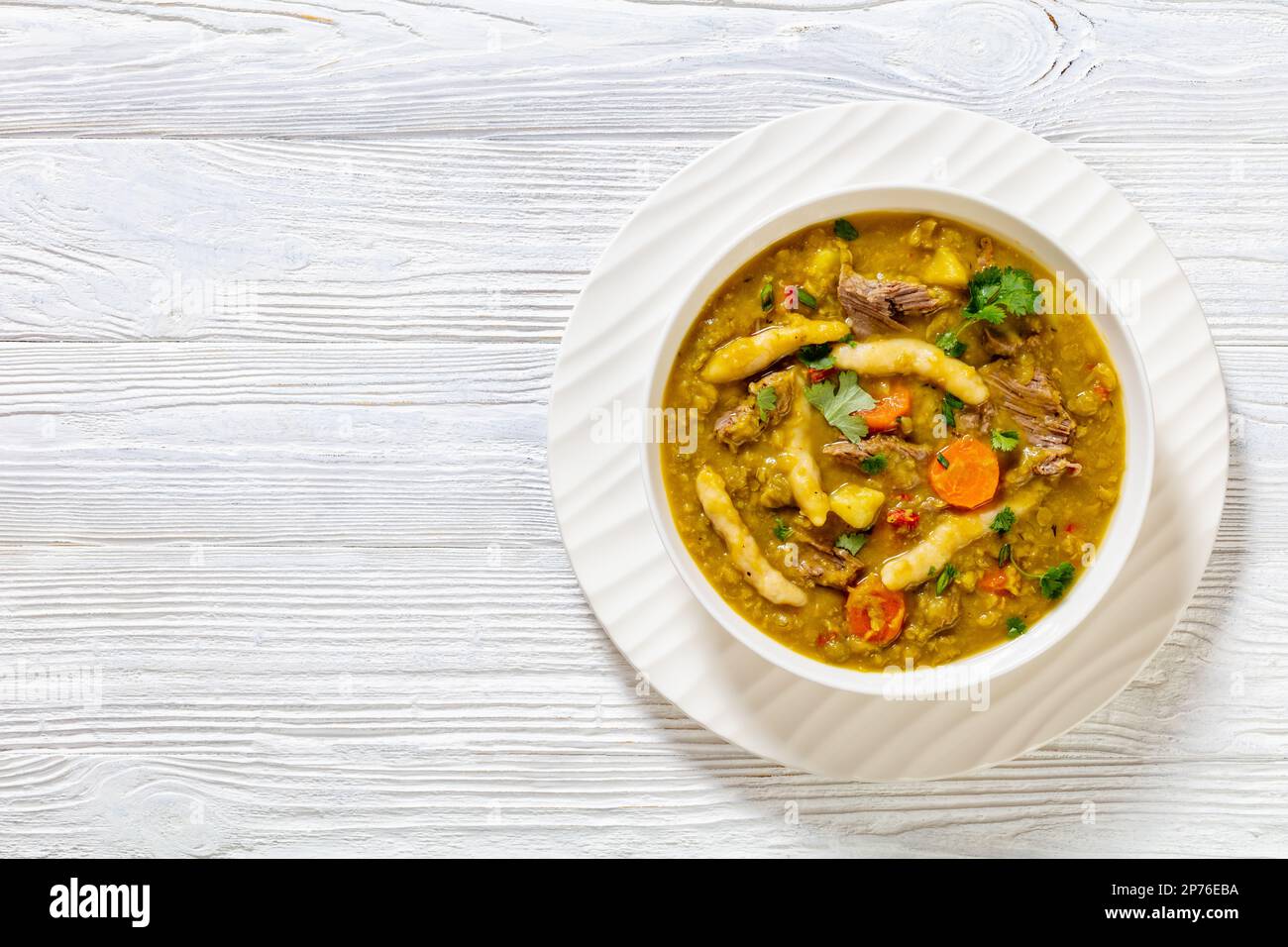 petits pois, soupe de petits pois avec boulettes, légumes et bœuf dans un bol blanc sur table en bois blanc, cuisine jamaïcaine, plat, espace copie Banque D'Images