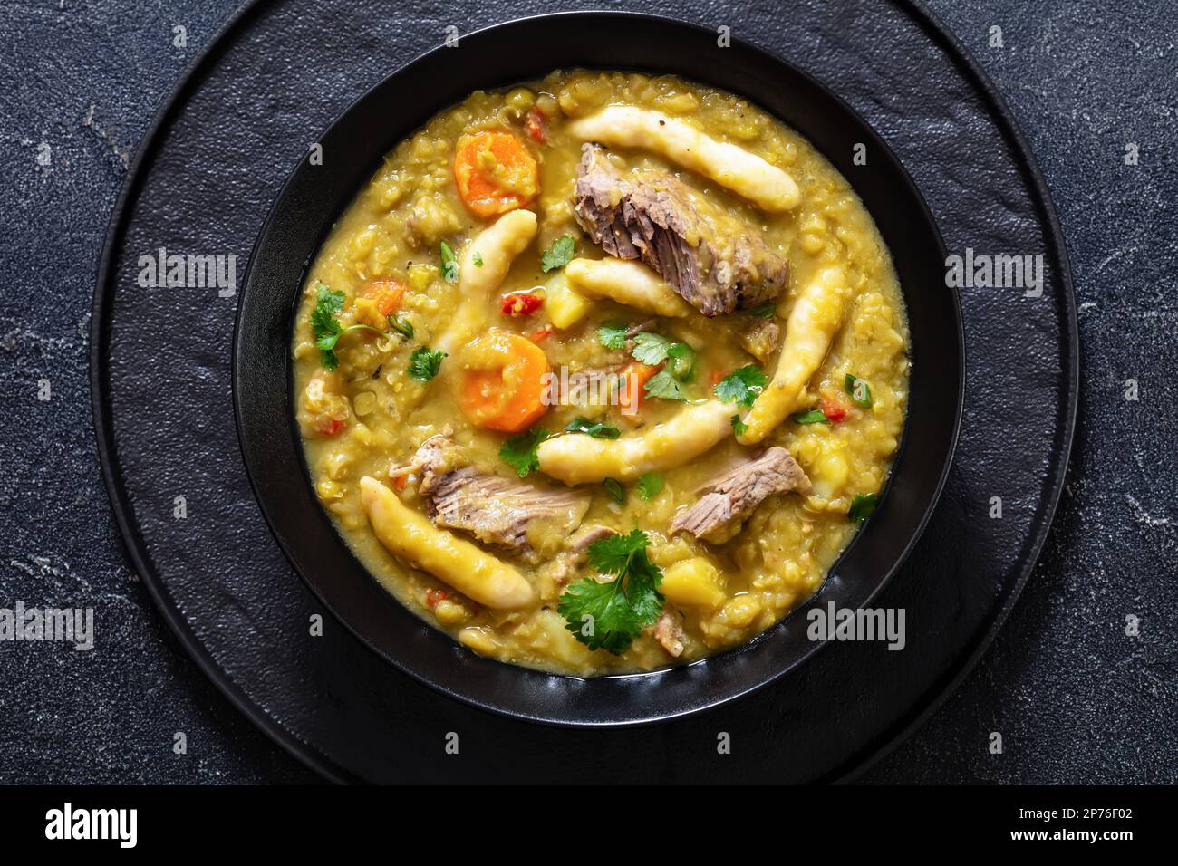 petits pois, soupe de petits pois avec boulettes et bœuf dans un bol noir sur table en béton, cuisine jamaïcaine, vue horizontale depuis le dessus, plat, gros plan Banque D'Images
