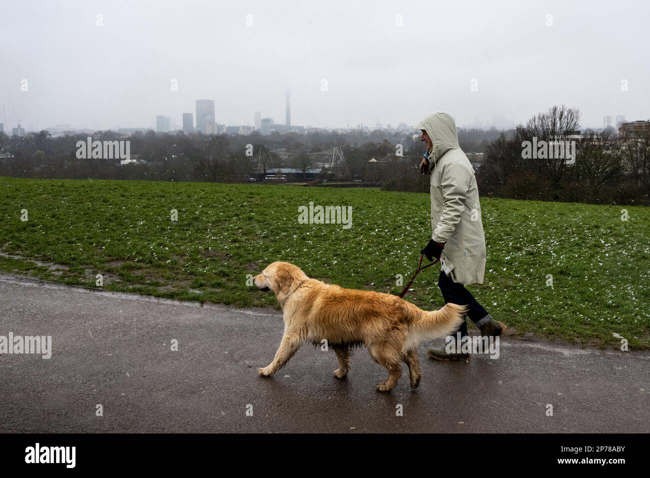 Londres, Royaume-Uni. 8 mars 2023. Météo au Royaume-Uni – Une femme marche avec son chien avec la Tour BT le seul point de repère visible reconnaissable lorsqu'une douche à neige arrive au sommet de Primrose Hill. Le bureau met a émis un avertissement jaune pour une grande partie du Royaume-Uni pour la neige et la glace. Credit: Stephen Chung / Alay Live News Banque D'Images