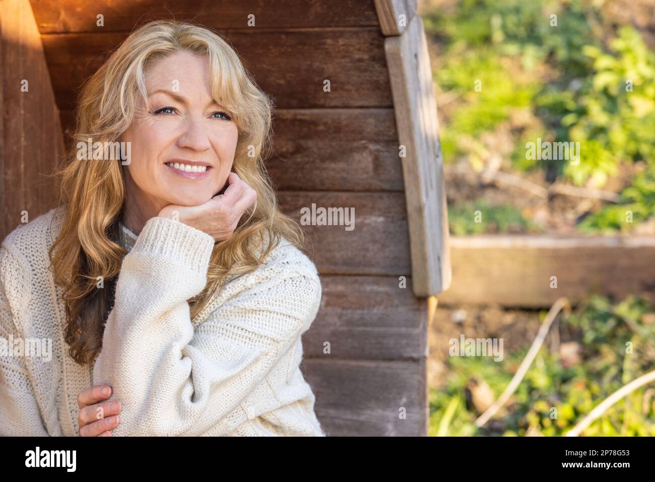 Belle femme d'âge moyen, attentionnés, assise à l'extérieur pour se détendre Banque D'Images