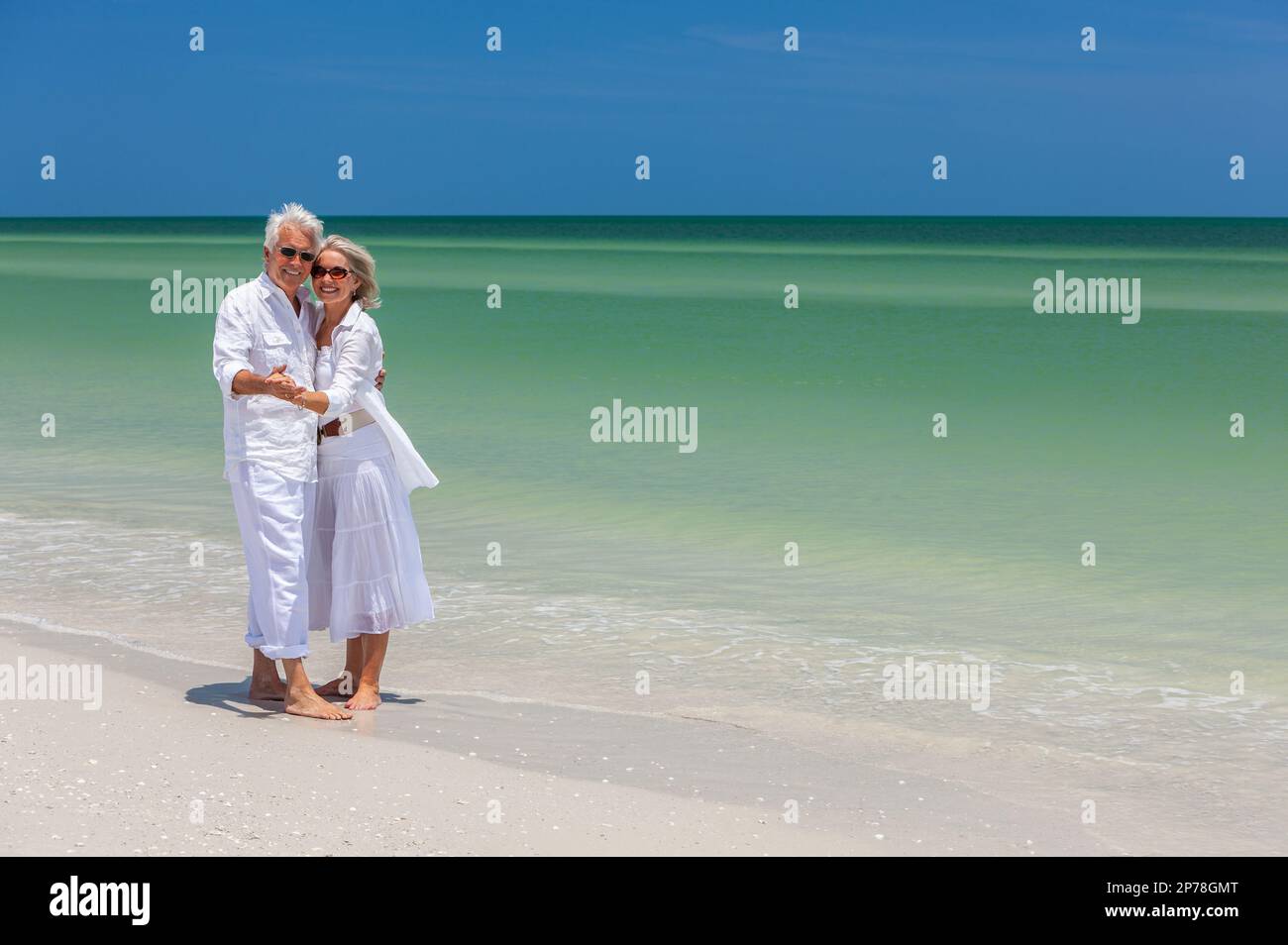 Happy senior man and woman couple dancing et tenir la main sur une plage tropicale déserte avec un ciel bleu clair Banque D'Images