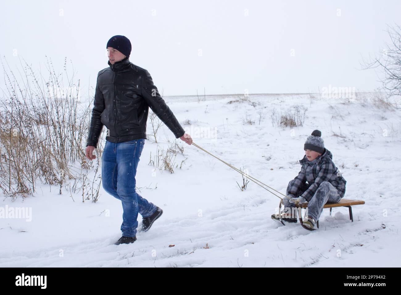le frère aîné sur des traîneaux tire le jeune frère Banque D'Images