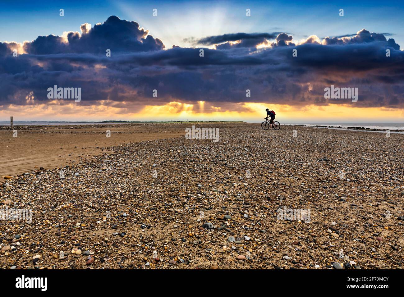 Cycliste sur plage de galets, île marémotrice en déroute, ciel nocturne, péninsule de point en déroute, Hull, Yorkshire, Angleterre, Royaume-Uni Banque D'Images