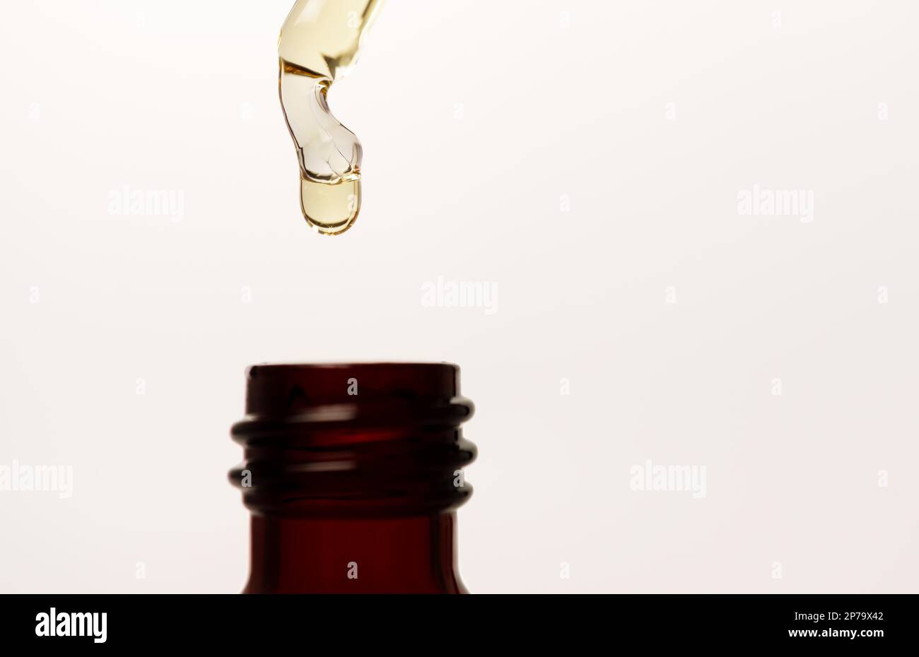 Gros plan d'une pipette de sérum avec chute sur fond blanc Banque D'Images