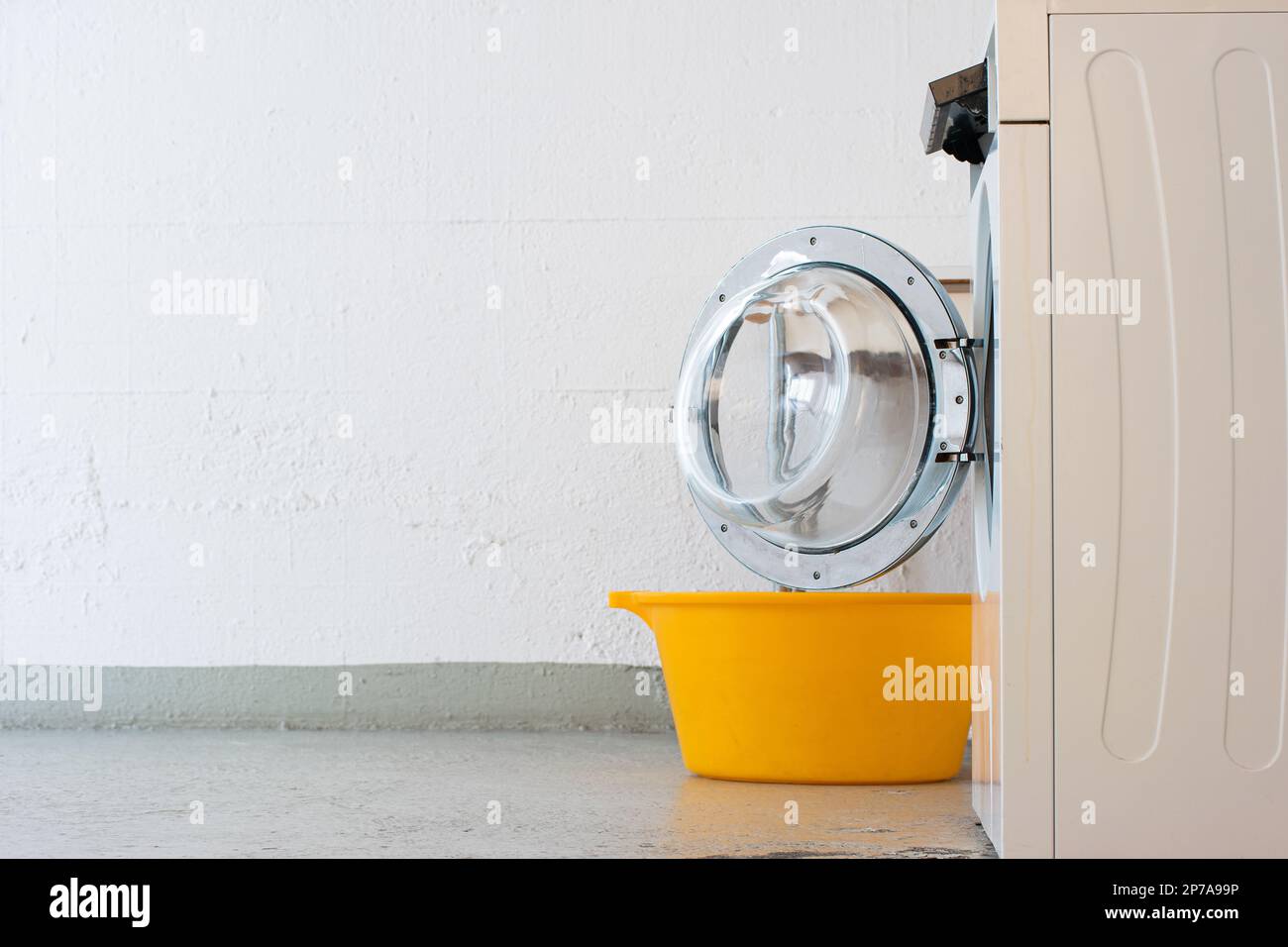 Machine à laver la chambre Landry porte ouverte et panier en plastique jaune. Pas de personne avec vue latérale. Banque D'Images