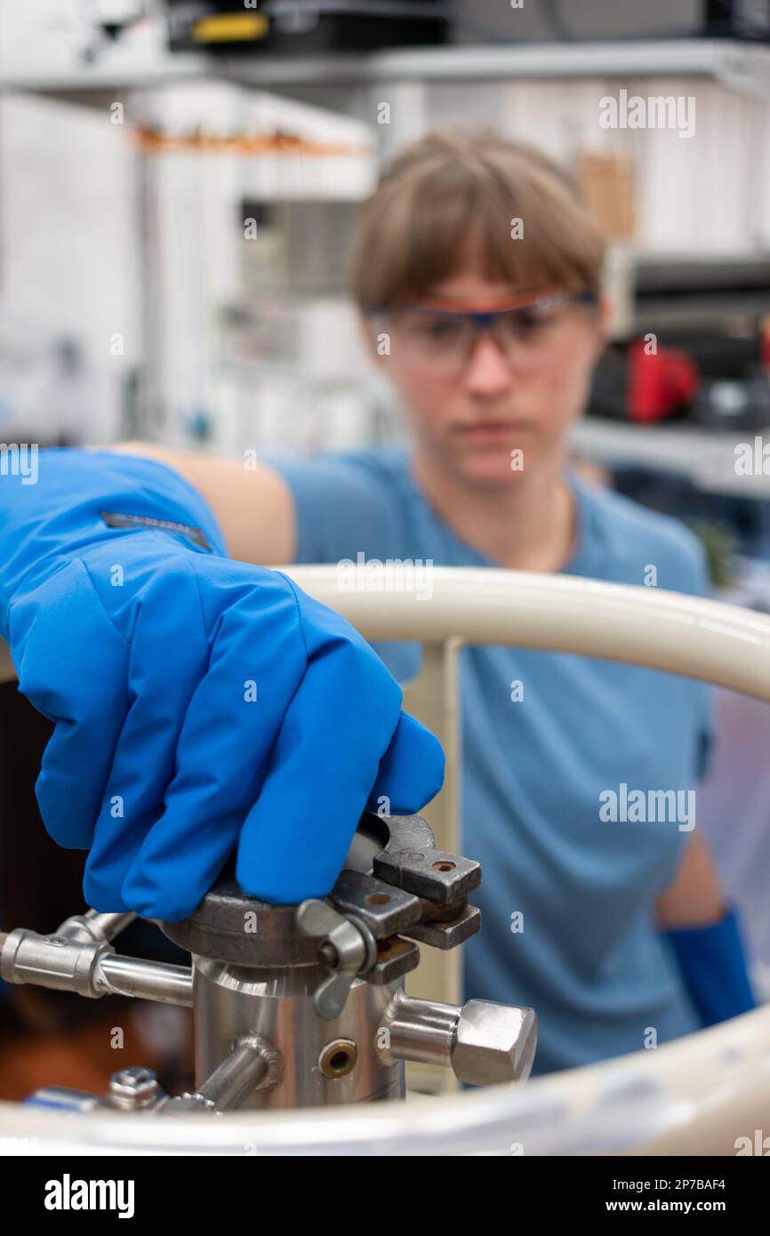 Femme scientifique exploitant un grand réservoir d'azote liquide avec sa main gantée de sécurité. Gros plan, faible profondeur de champ, non-focus, non reconnu Banque D'Images