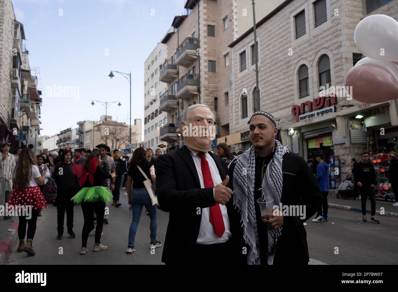 An Israeli in a mask depicting Prime Minister Benjamin Netanyahu poses for a photo on Agrippas Street in Jerusalem during a street party on the Jewish holiday of Purim, Wednesday, March 8, 2023. The Jewish holiday of Purim commemorates the Jews salvation from genocide in ancient Persia, as recounted in the Book of Esther. (AP Photo/Maya Alleruzzo) Banque D'Images