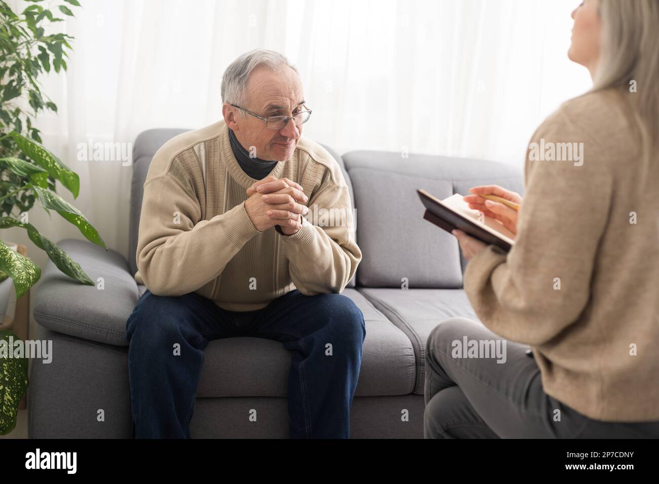 Homme senior patient et jeune femme soignant travailleur médical en uniforme tenir le presse-papiers notant les informations personnelles parler écoute le client parler Banque D'Images