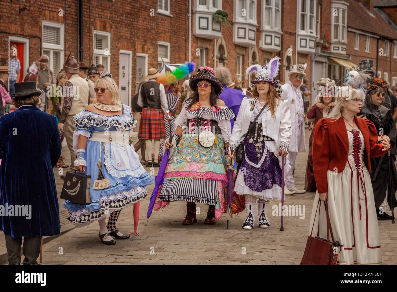 Un groupe de femmes steampunks vêtues d'Alice bien que les vêtements inspirés du verre aient l'air dans cette scène surréaliste de rue. Banque D'Images