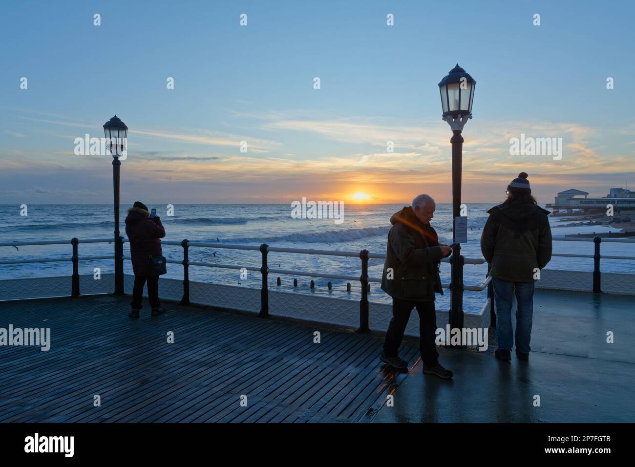 Les gens qui profitent d'un coucher de soleil spectaculaire vu de Worthing Pier, West Sussex Angleterre Royaume-Uni Banque D'Images
