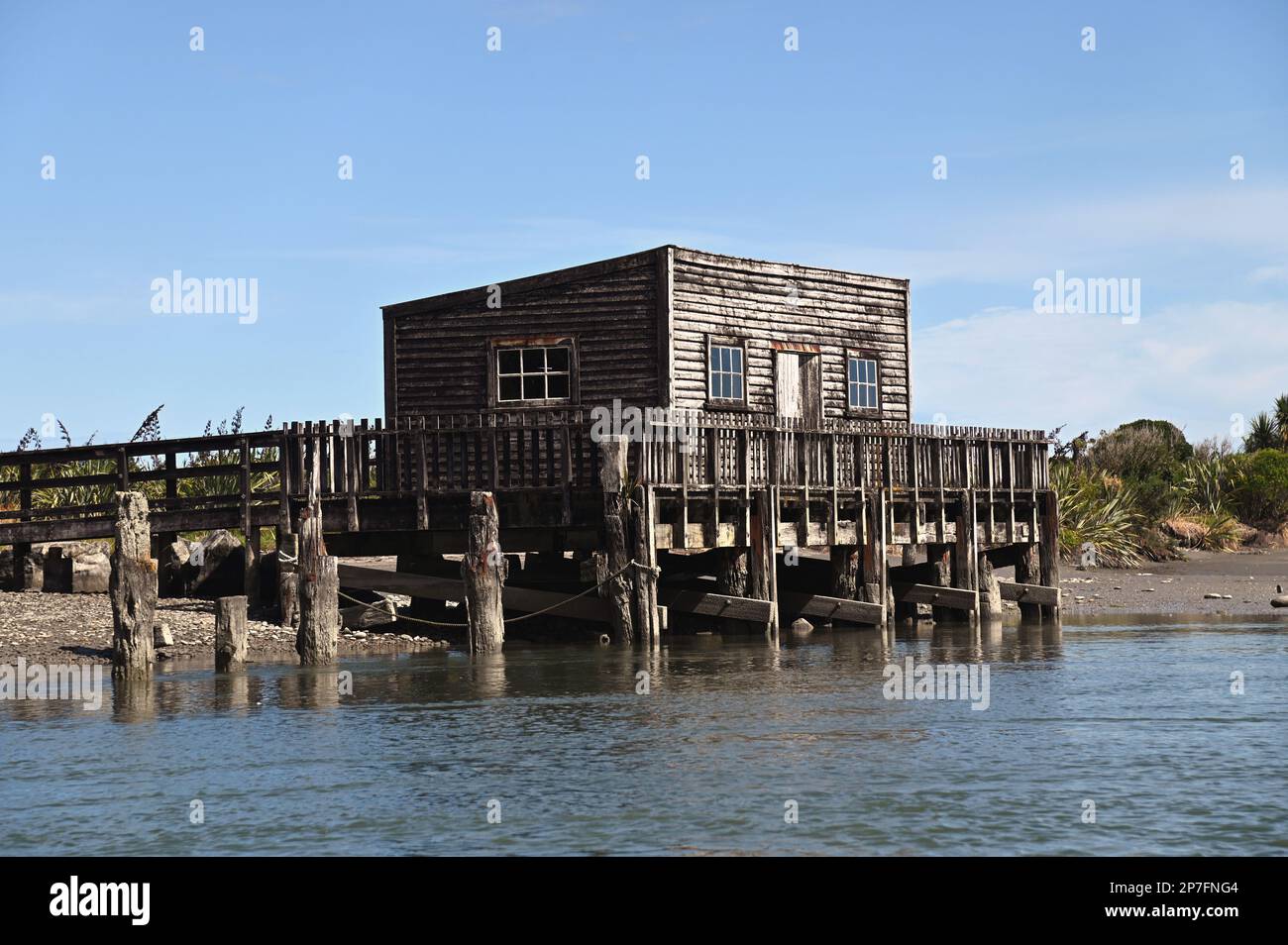 Le quai, la jetée et la maison de bateau à la colonie de la côte ouest d'Okarito. Pendant la ruée vers l'or de 1860s, Okarito a vu plus de 500 mineurs débarquer en une journée. Banque D'Images