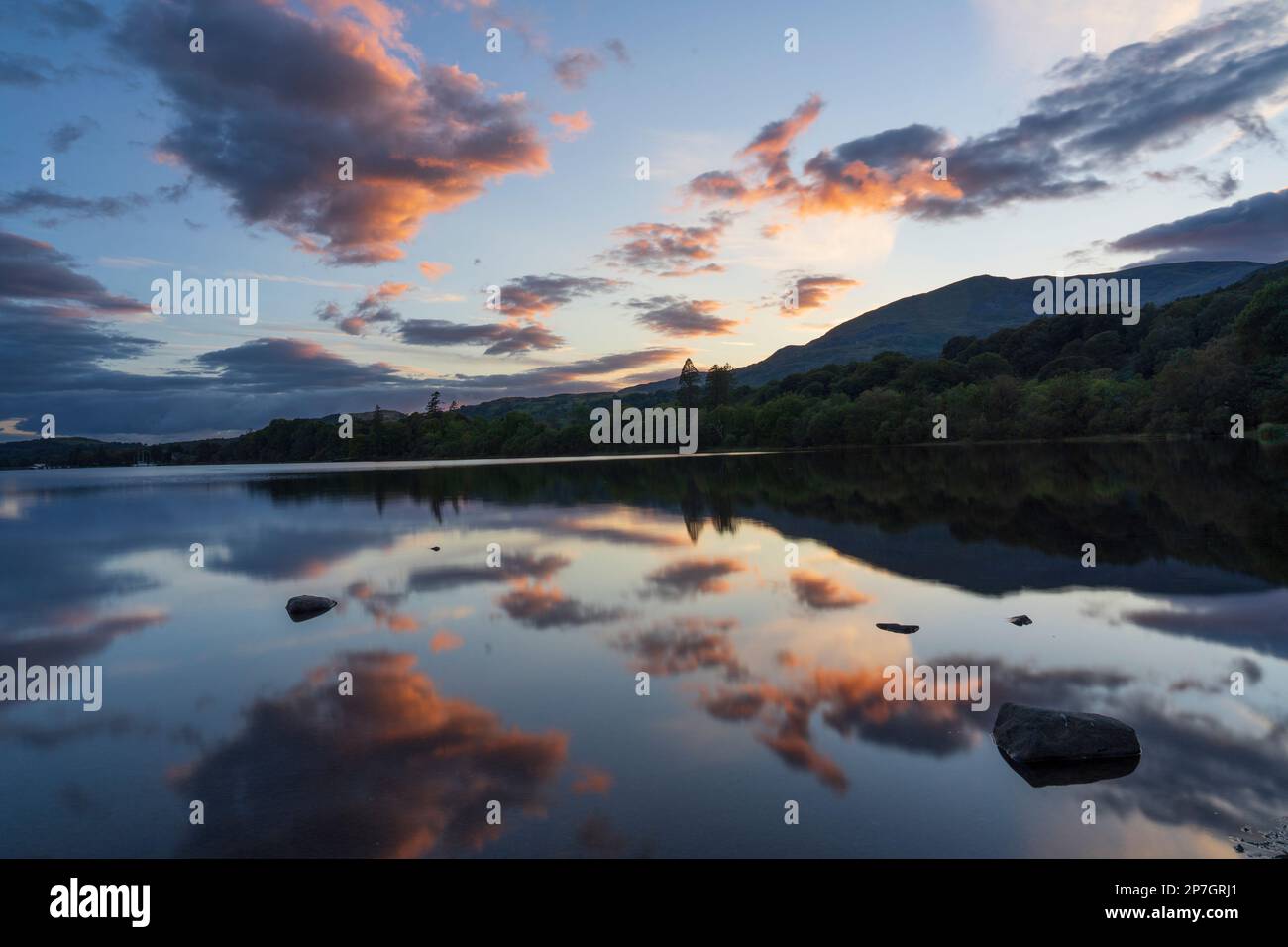 Angleterre, Cumbria, parc national de Lake District. Les collines du Lakeland et un coucher de soleil coloré se reflètent sur la face fixe de Coniston Water. Banque D'Images