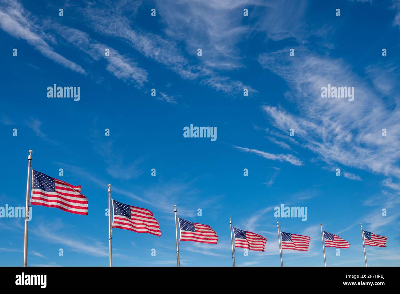 Rangée de drapeaux américains soufflant dans le vent avec ciel bleu vif et espace de copie. Banque D'Images
