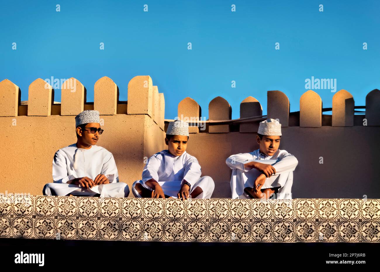 Garçons avec des chapeaux kuma sur le toit, Nizwa, Oman Banque D'Images