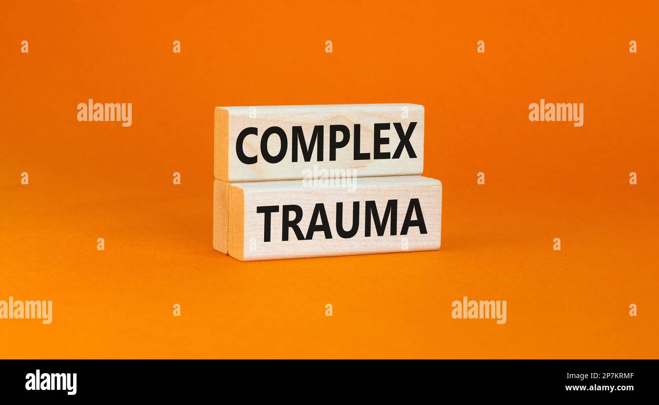 Symbole de traumatisme complexe. Concept mots trauma complexe sur bloc de bois. Belle table orange fond orange. Psychologie des affaires complexe trauma conc Banque D'Images