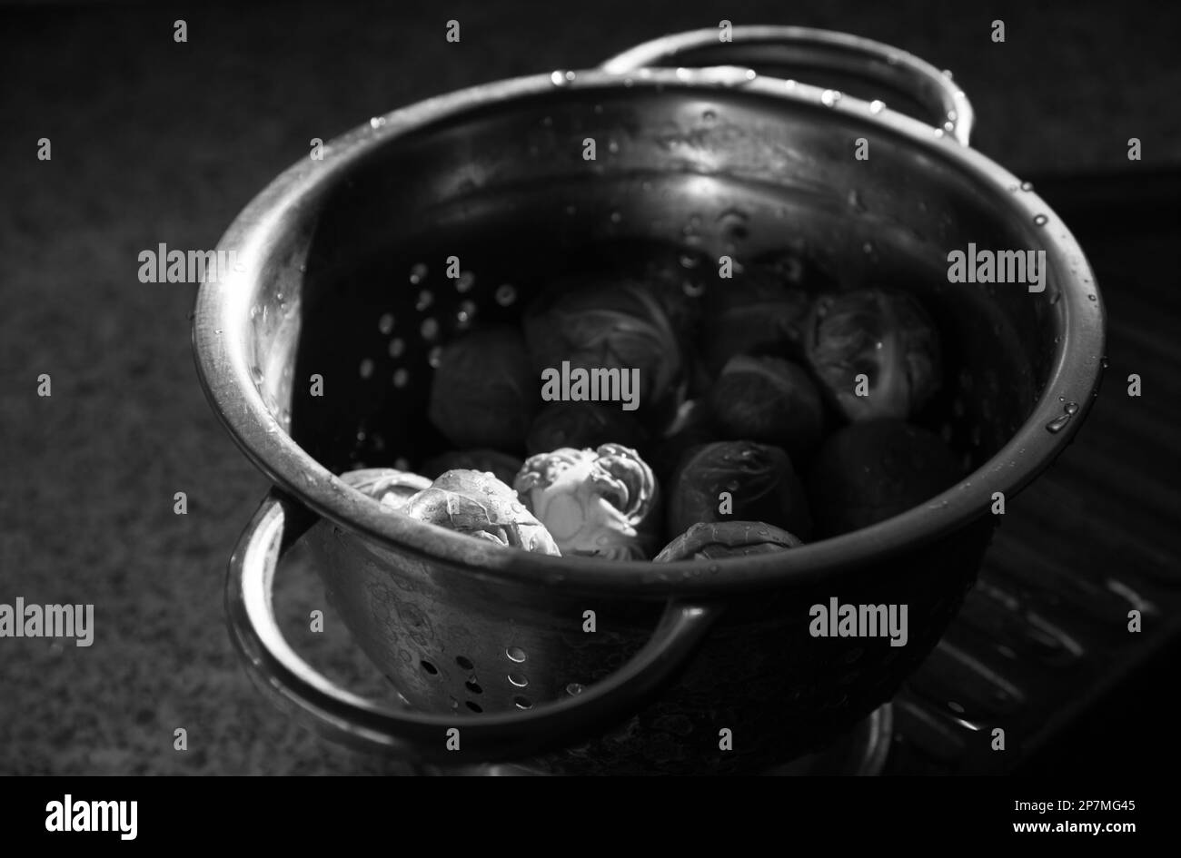Bruxellois vert non cuit frais et propre dans une vieille passoire en métal avec des gouttes d'eau. Mise au point sélective. Cuisine de style de vie candiée. Noir blanc Banque D'Images