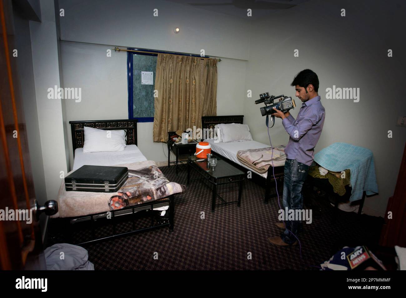 A Pakistani video cameraman films the inside view of a hotel room allegedly used by arrested American Muslims in Karachi, Pakistan on Monday, Dec. 14, 2009. Pakistani police Monday seized luggage and a cell phone from a hotel where three of five Americans arrested on suspicion of militant links stayed, while a court ordered the men could not be deported until judges review the case. (AP Photo/Shakil Adil) Banque D'Images