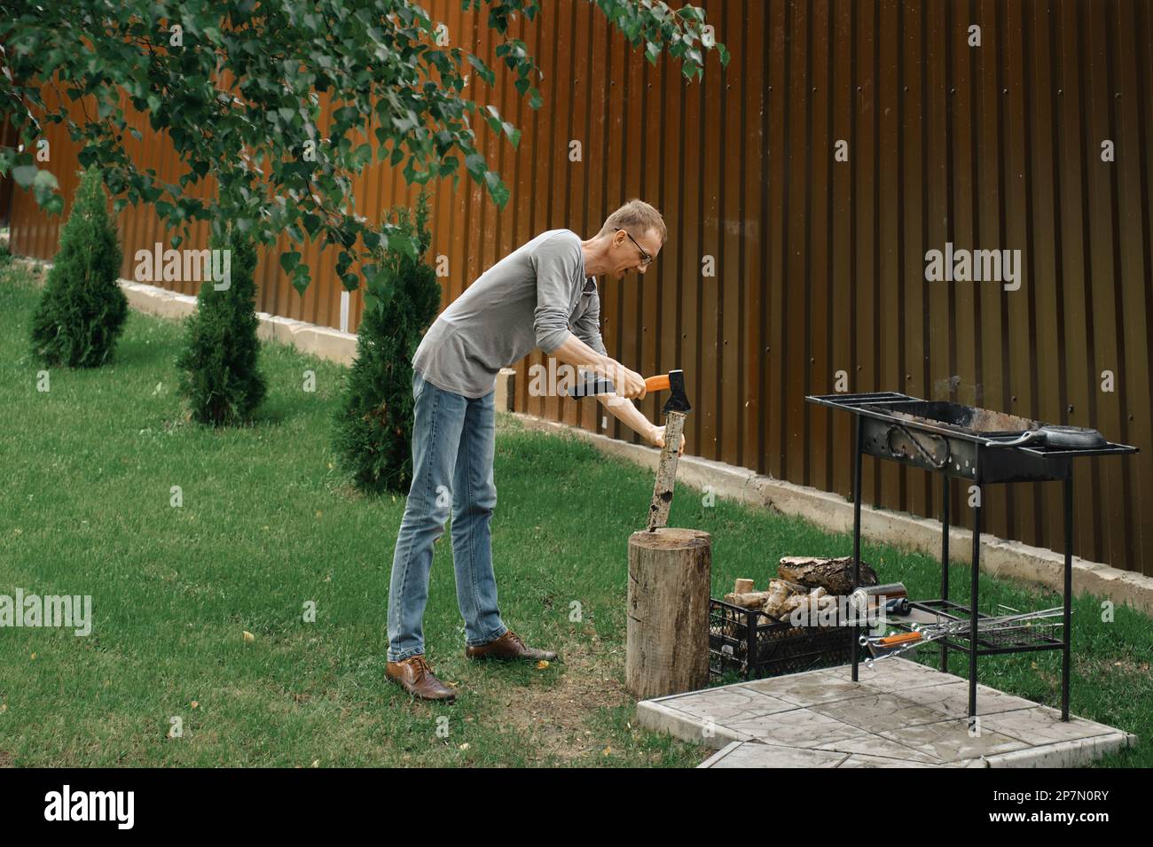 Homme hacher du bois près d'un barbecue Banque D'Images