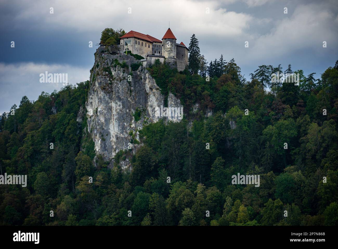Le château historique de Bled en été avec des nuages sombres et des arbres Banque D'Images