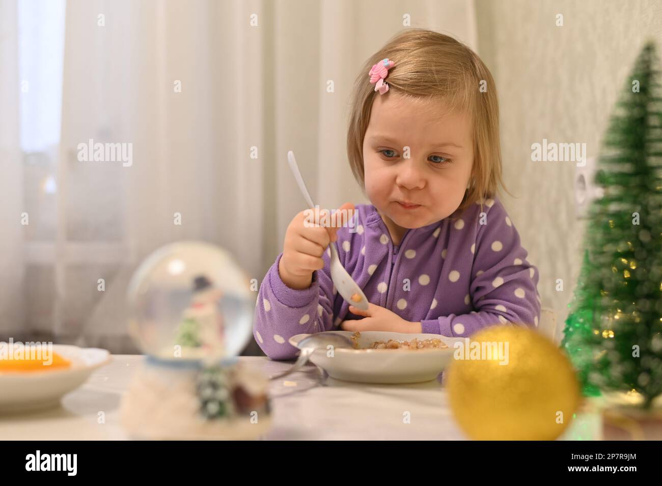 Une fille de 3 ans prend le petit-déjeuner le réveillon de Noël Banque D'Images