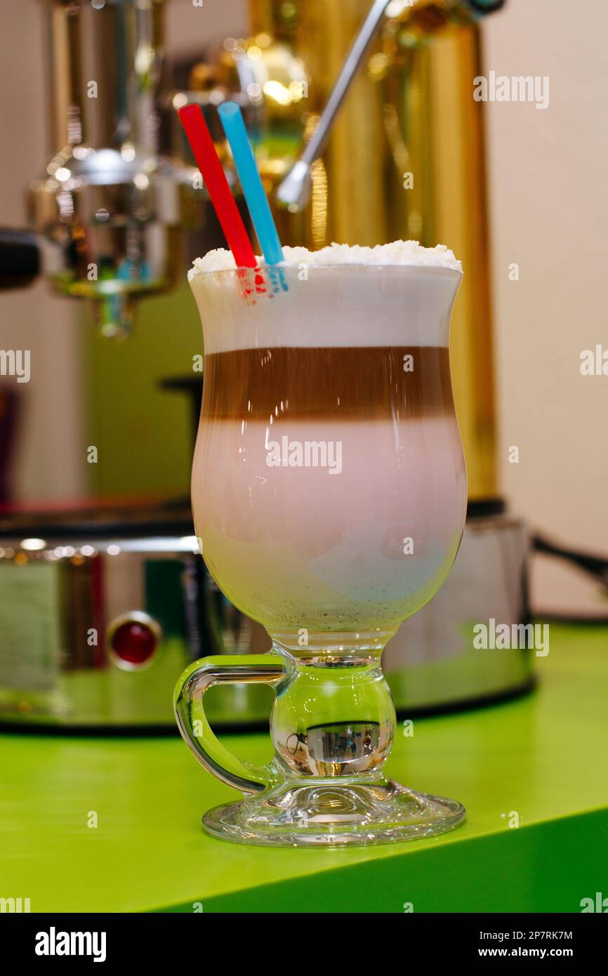 Cocktail café avec mousse et flocons de noix de coco avec deux pailles. Machine à café sur fond Banque D'Images