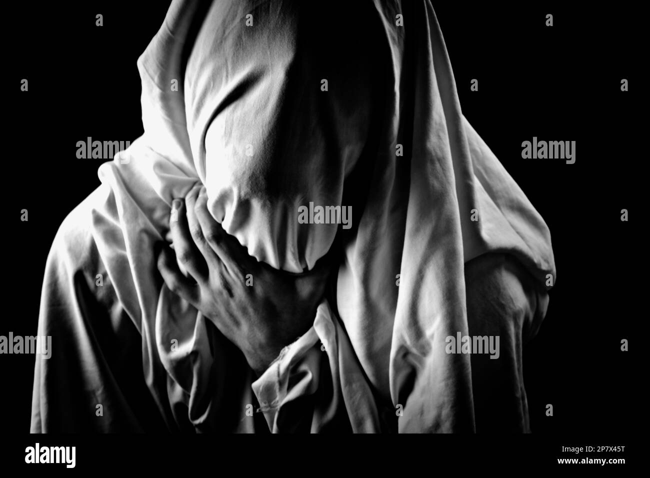 Personne embrassant son cou avec sa main, sous un voile blanc. Photo conceptuelle exprimant la suffocation et les désagréments humains. Poster en noir et blanc. Banque D'Images