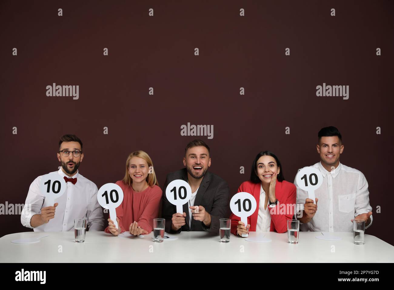 Panel de juges portant des affiches avec le score le plus élevé à la table sur fond marron Banque D'Images