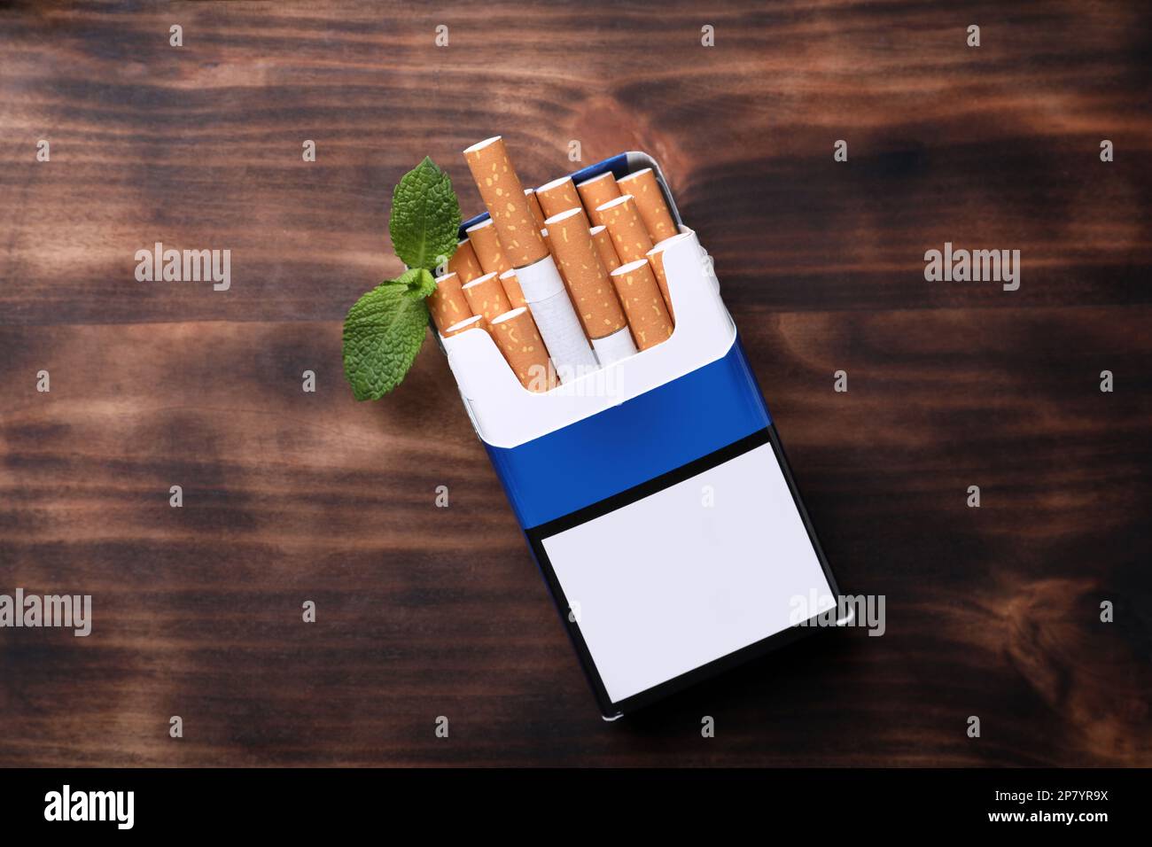 Paquet de cigarettes de menthol et feuilles de menthe sur table en bois, plat Banque D'Images