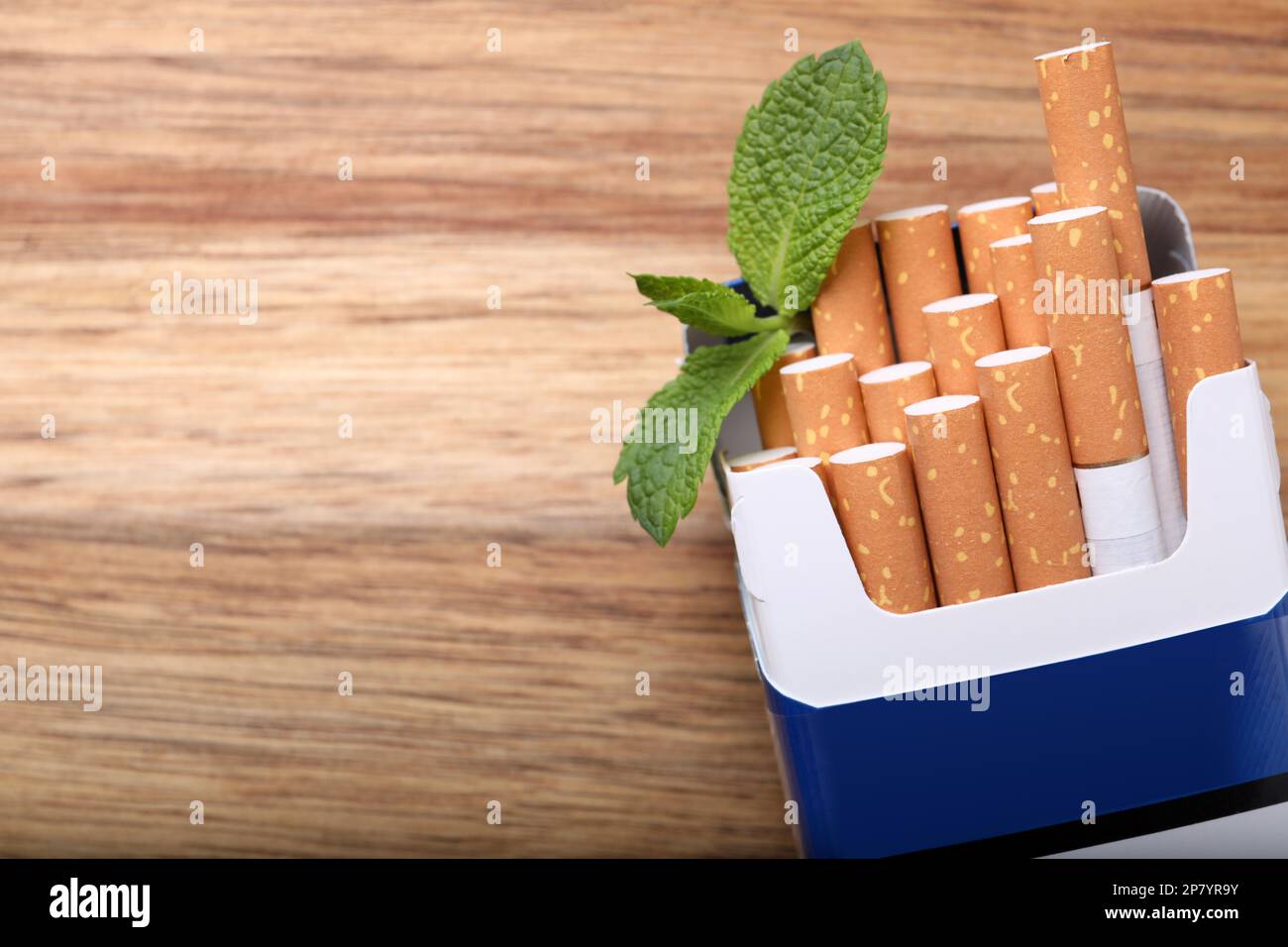 Paquet de cigarettes de menthol et feuilles de menthe sur table en bois, plat. Espace pour le texte Banque D'Images