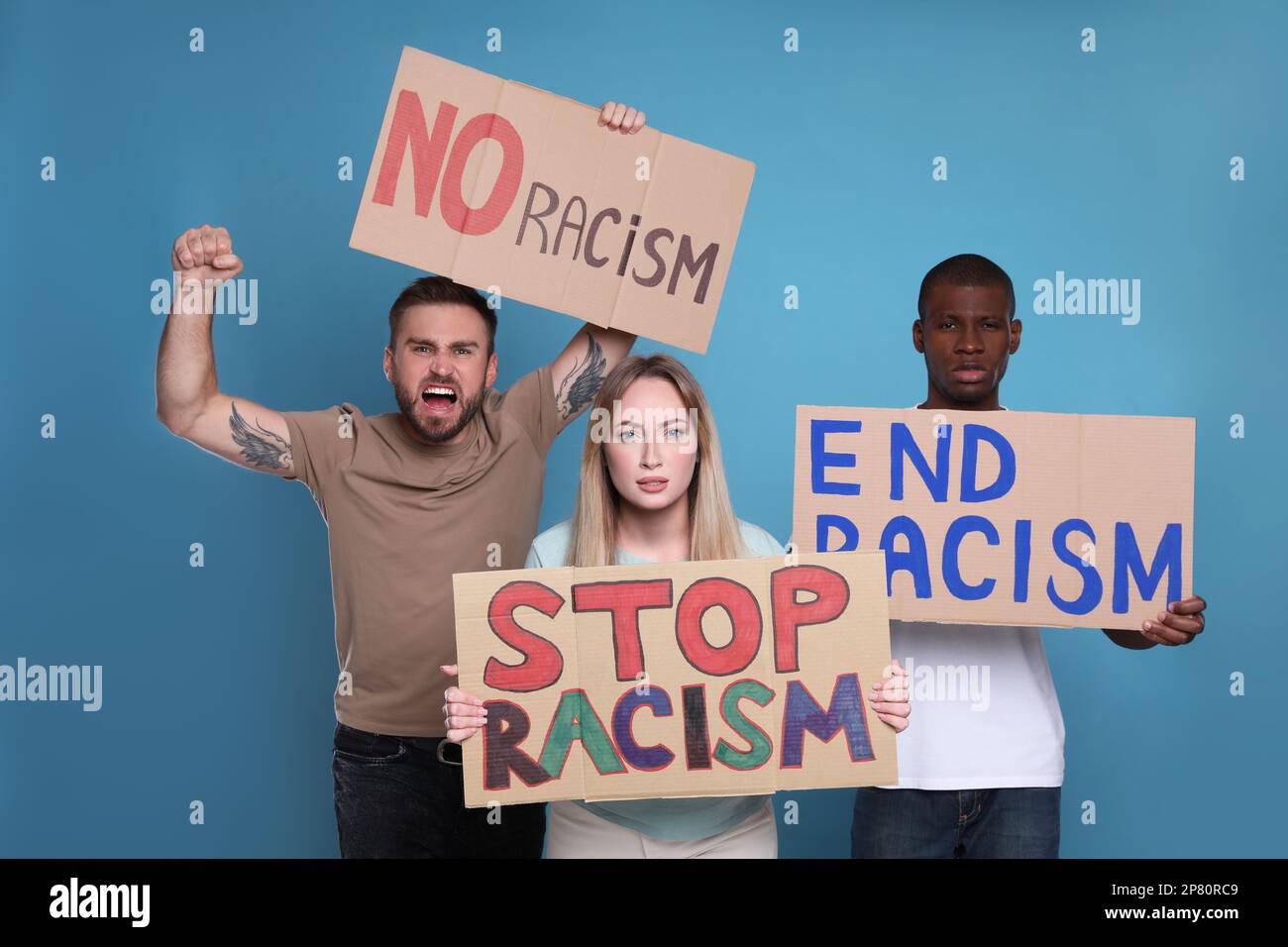 Les manifestants manifestent différents slogans anti-racisme sur fond bleu clair. Personnes portant des signes avec des phrases Banque D'Images