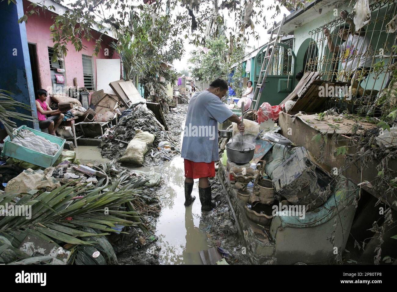 A survivor cooks his meal outside his home at the typhoon-damaged town of Bagong Silangan, Quezon City, north of Manila, Philippines on Sunday Oct. 4, 2009. Landslides buried two families in the Philippines as they sheltered in their homes from Asia's latest deadly typhoon, which killed several people and left more than a dozen flooded villages cut off. (AP Photo/Aaron Favila) Banque D'Images