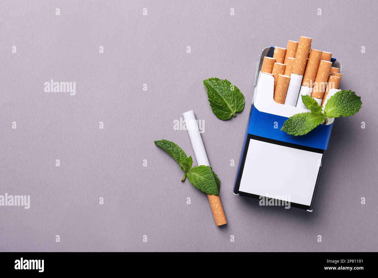 Paquet de cigarettes de menthol et feuilles de menthe sur fond gris, plat. Espace pour le texte Banque D'Images