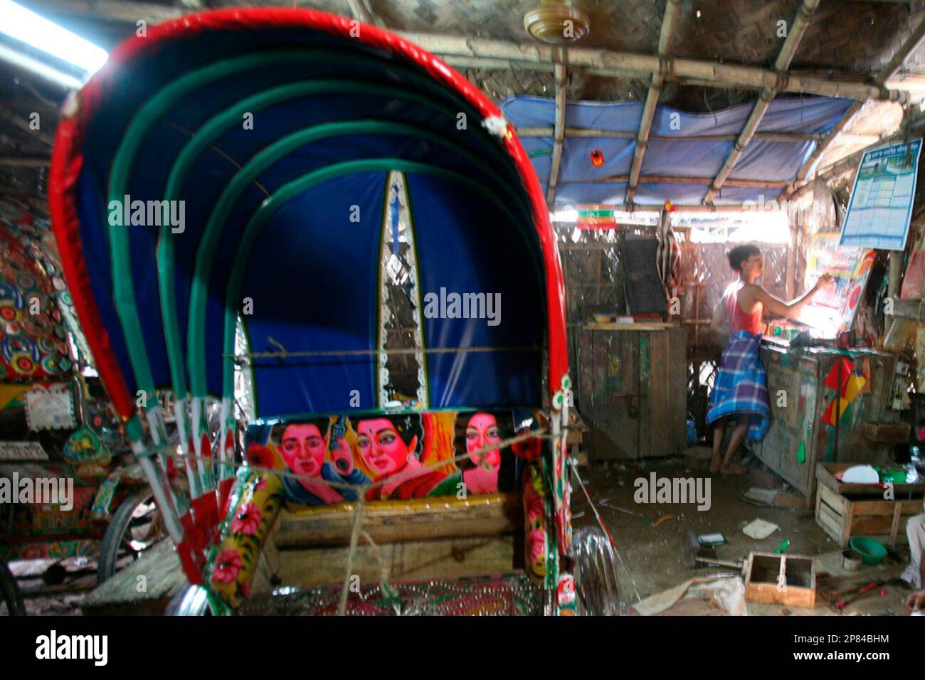 Rasid, a rickshaw painter, paints a tin plate fixed to the lower rear