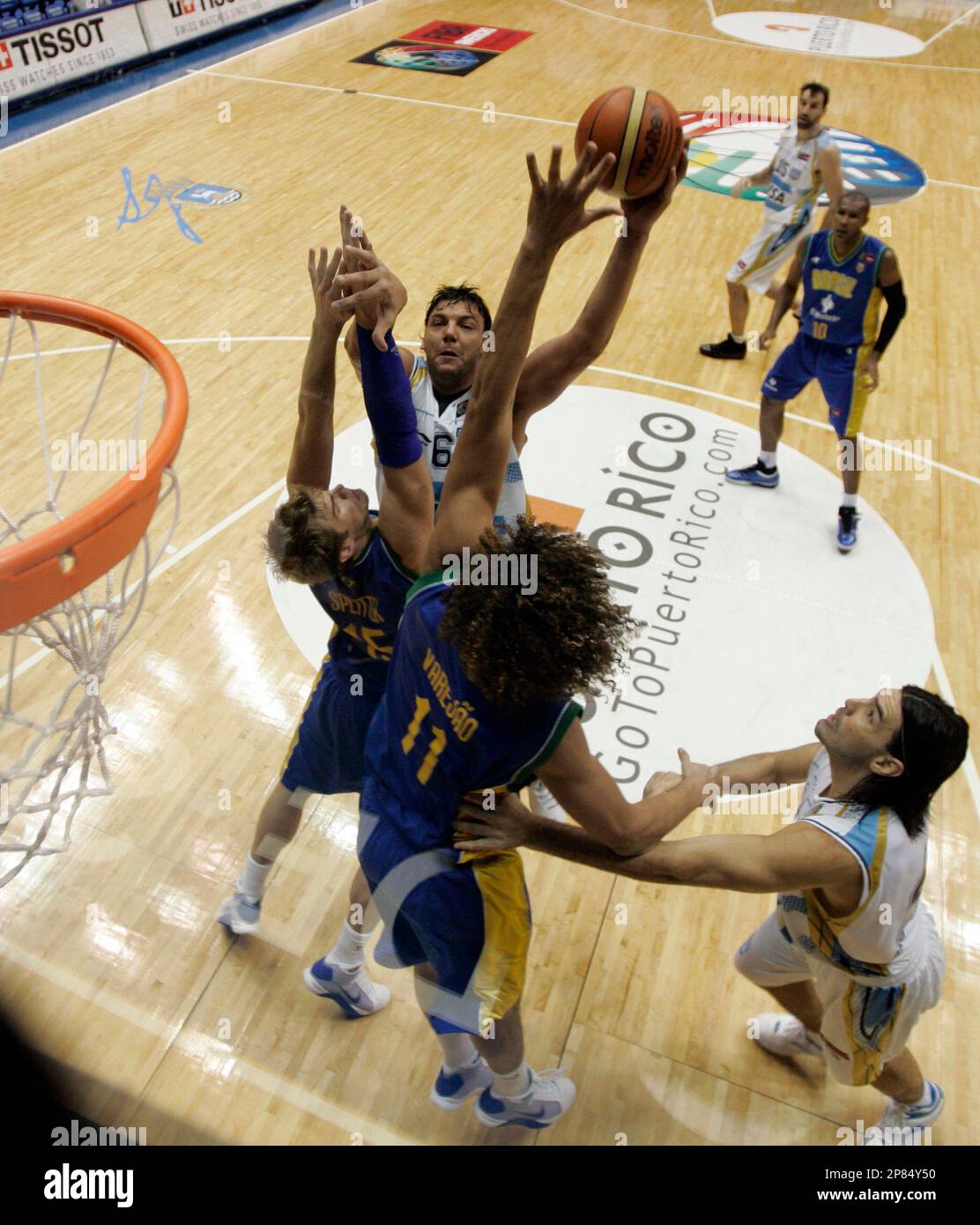 Argentina's Roman Gonzalez, second left, shoots over the defense of Brazil's Tiago Splitter, left, and Anderson Varejao (11) as teammate Luis Scola looks on, during a FIBA Americas Championship basketball game in San Juan, Friday, Aug. 28, 2009. Brazil won 76-67. (AP Photo/Ricardo Arduengo) Banque D'Images