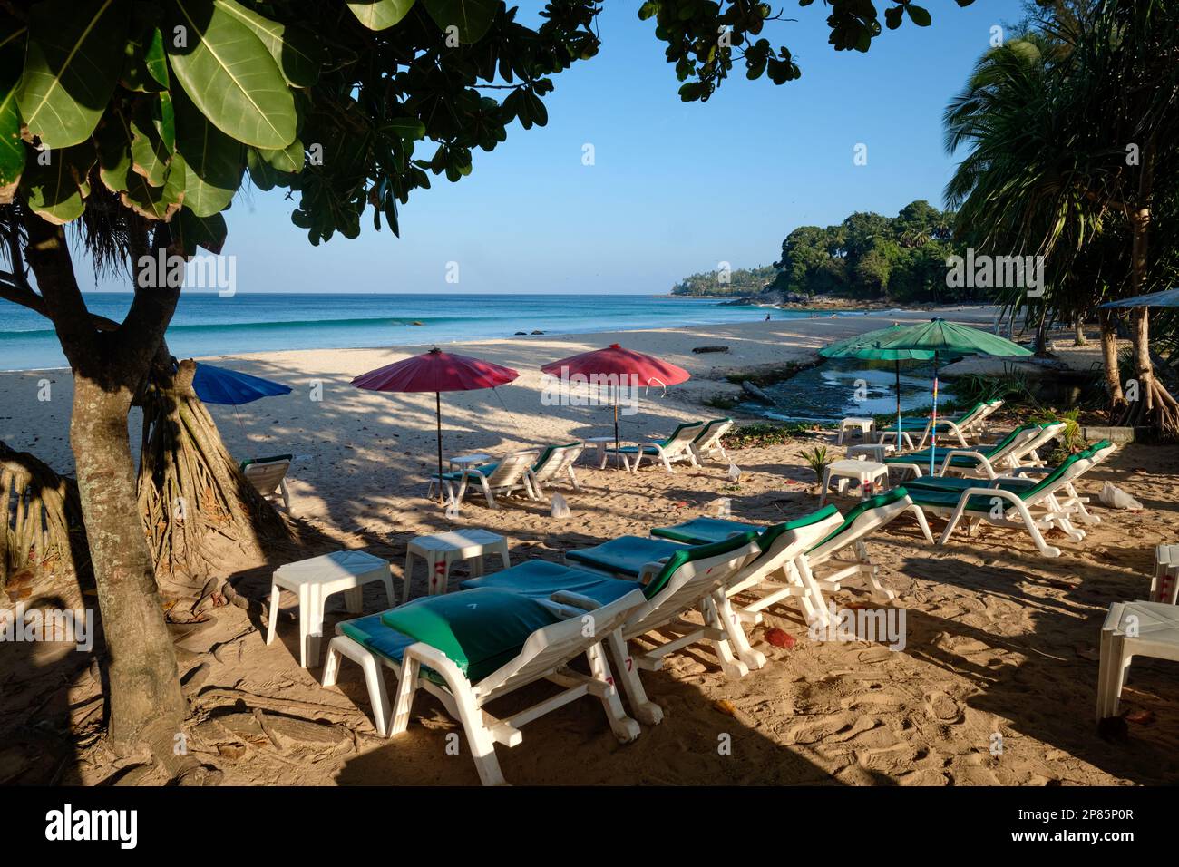 Tôt le matin, vue sur Surin Beach, Phuket, Thaïlande du Sud, avec sable blanc et bordé de palmiers et d'arbres, et des chaises de plage vides Banque D'Images