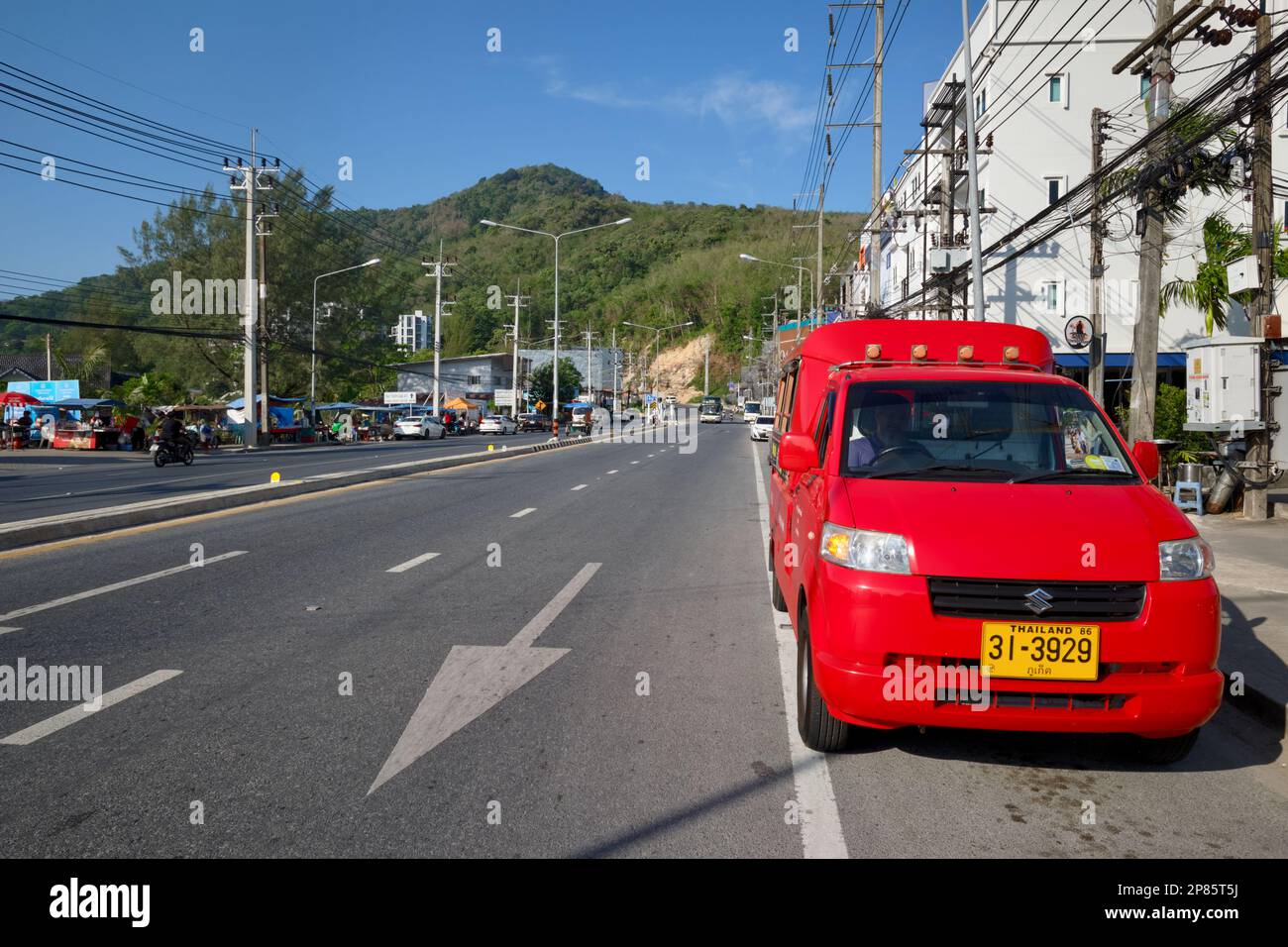 Rouge un tuk-tuk, un taxi local à quatre roues, est stationné dans la rue principale qui traverse Kamala, Green Hills dans le b/g ; Kamala Beach, Phuket, Thailand Banque D'Images