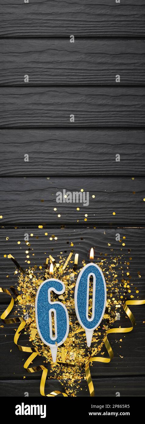 Numéro 60 bougie de célébration bleue et confetti d'or sur fond de bois foncé. carte d'anniversaire 60th. Concept anniversaire et anniversaire. Bannière verticale. Banque D'Images
