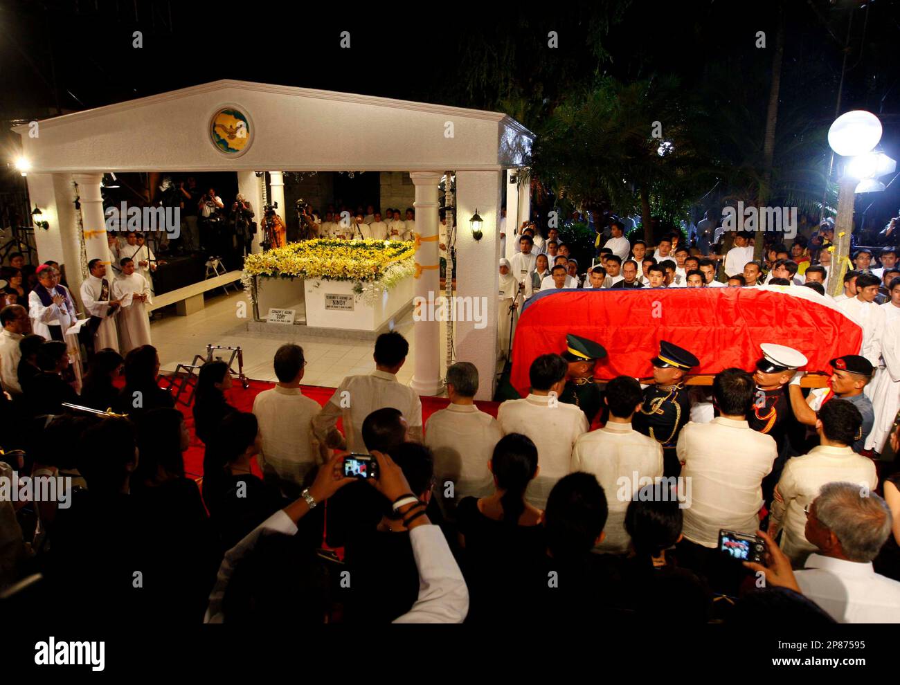 Philippine police and military officers carry the casket containing the remains of the late Philippine President Corazon Aquino during a funeral rite at Manila Memorial Park, Manila, Wednesday, Aug. 5, 2009. Former President Corazon Aquino was buried in her family mausoleum Wednesday with hundreds of thousands of supporters wearing her signature yellow color and professing gratitude to the woman who restored democracy at high personal cost. Aquino died Saturday at age 76 after a yearlong battle with colon cancer. (AP Photo/Dennis M. Sabangan/pool) Banque D'Images