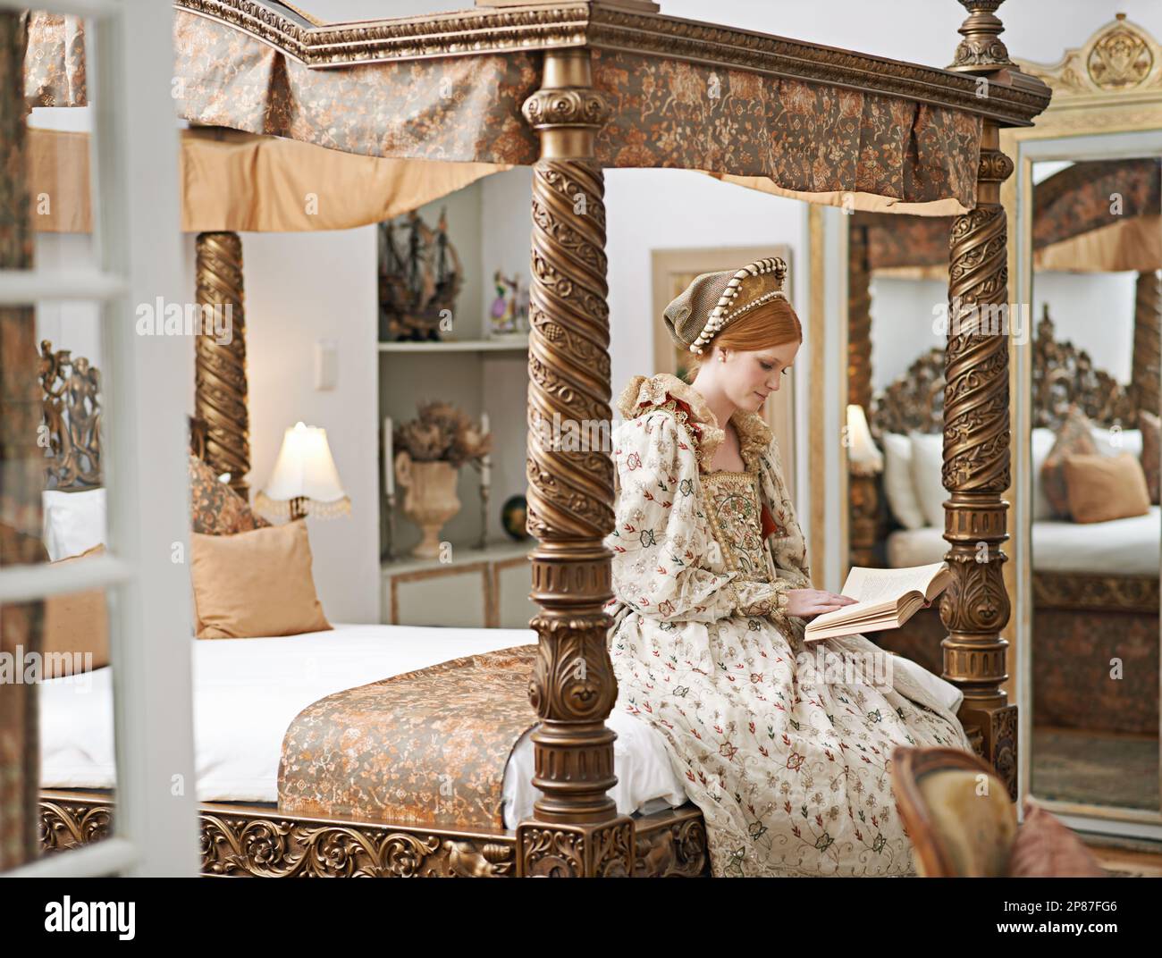 Solitude du lit. une élégante noble femme lisant dans sa chambre de palais. Banque D'Images