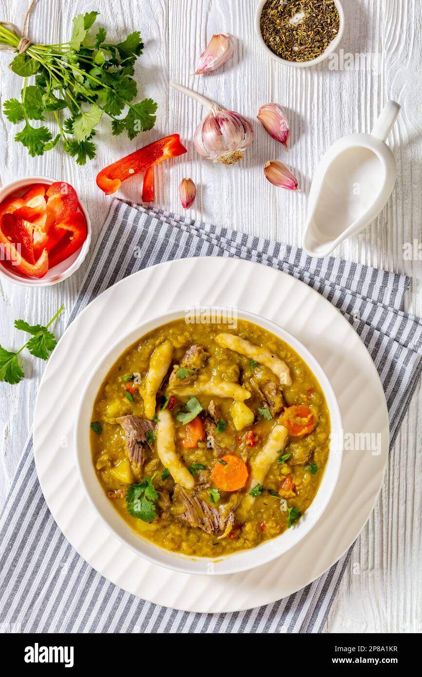 petits pois, soupe de petits pois avec boulettes, légumes et bœuf dans un bol blanc sur table en bois blanc, cuisine jamaïcaine, vue verticale Banque D'Images