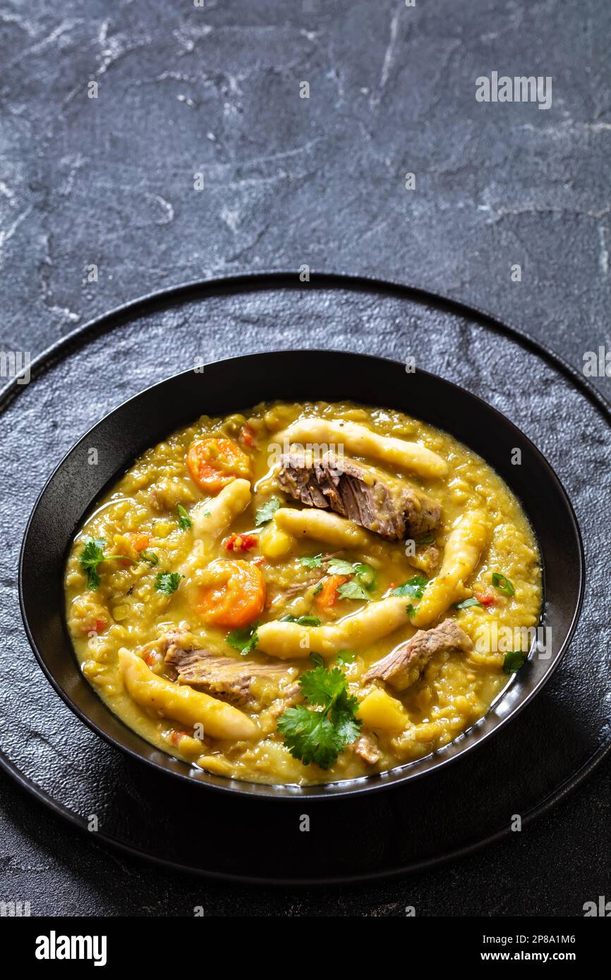 petits pois, soupe de petits pois avec boulettes et bœuf dans un bol noir sur table en béton, cuisine jamaïcaine, vue verticale, espace libre Banque D'Images