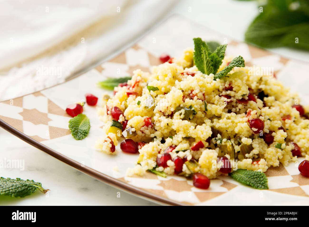 Salade de couscous avec des feuilles de grenade et de menthe. Banque D'Images