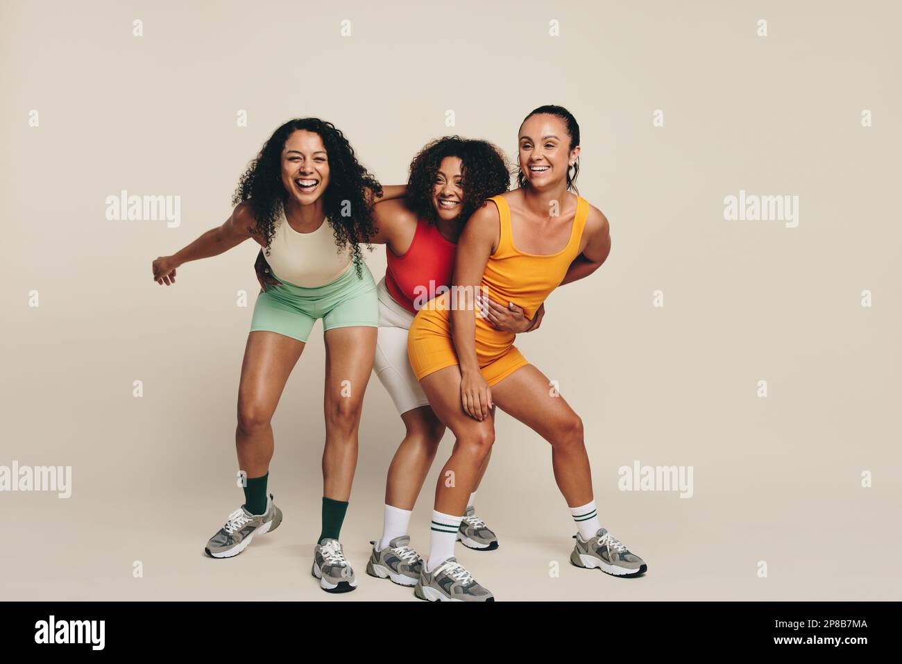Groupe de jeunes athlètes féminines riant et s'amusant dans les vêtements de fitness, célébrant leur amour pour le sport et l'exercice. Joyeux jeune sportif dem Banque D'Images