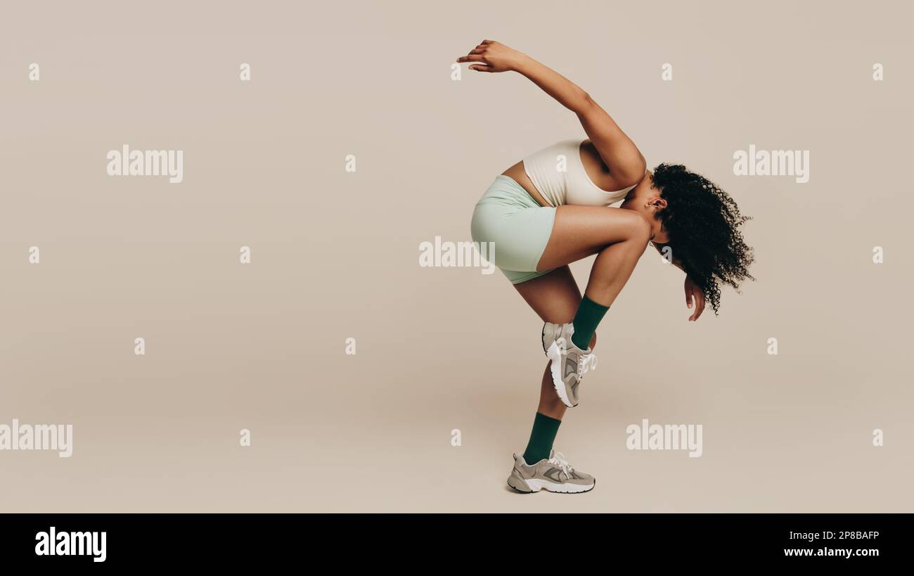 Femme avec une posture d'entraînement souple, exprimant son sportivité. Une athlète féminine fait des mouvements corporels gracieux dans le cadre de sa tonne musculaire Banque D'Images