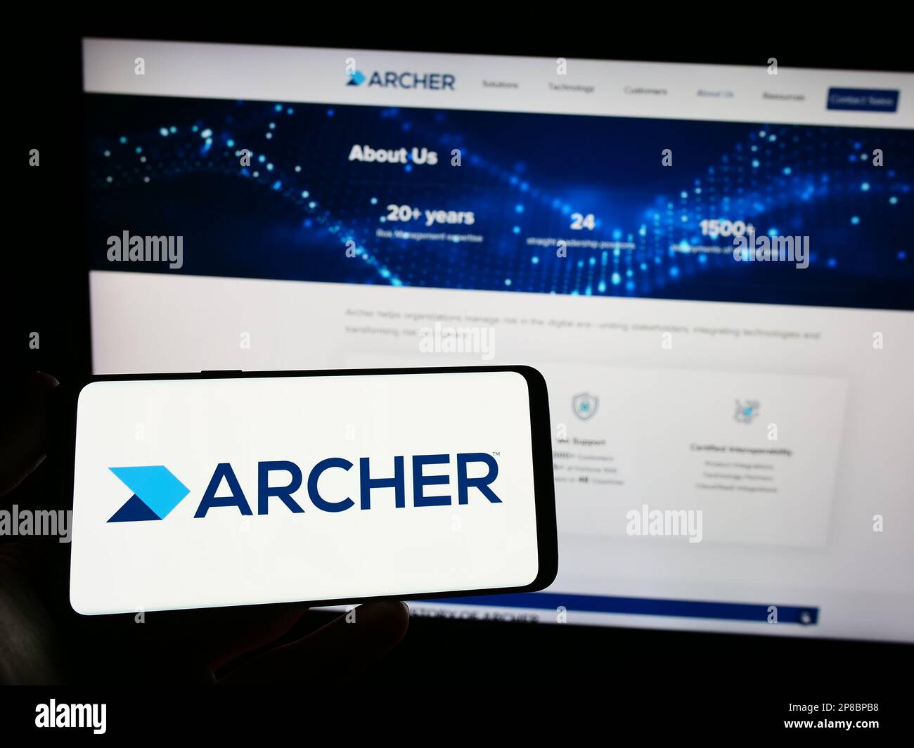 Personne détenant un smartphone portant le logo du logiciel de gestion des risques Archer (RSA Security) à l'écran, devant le site Web. Mise au point sur l'affichage du téléphone. Banque D'Images
