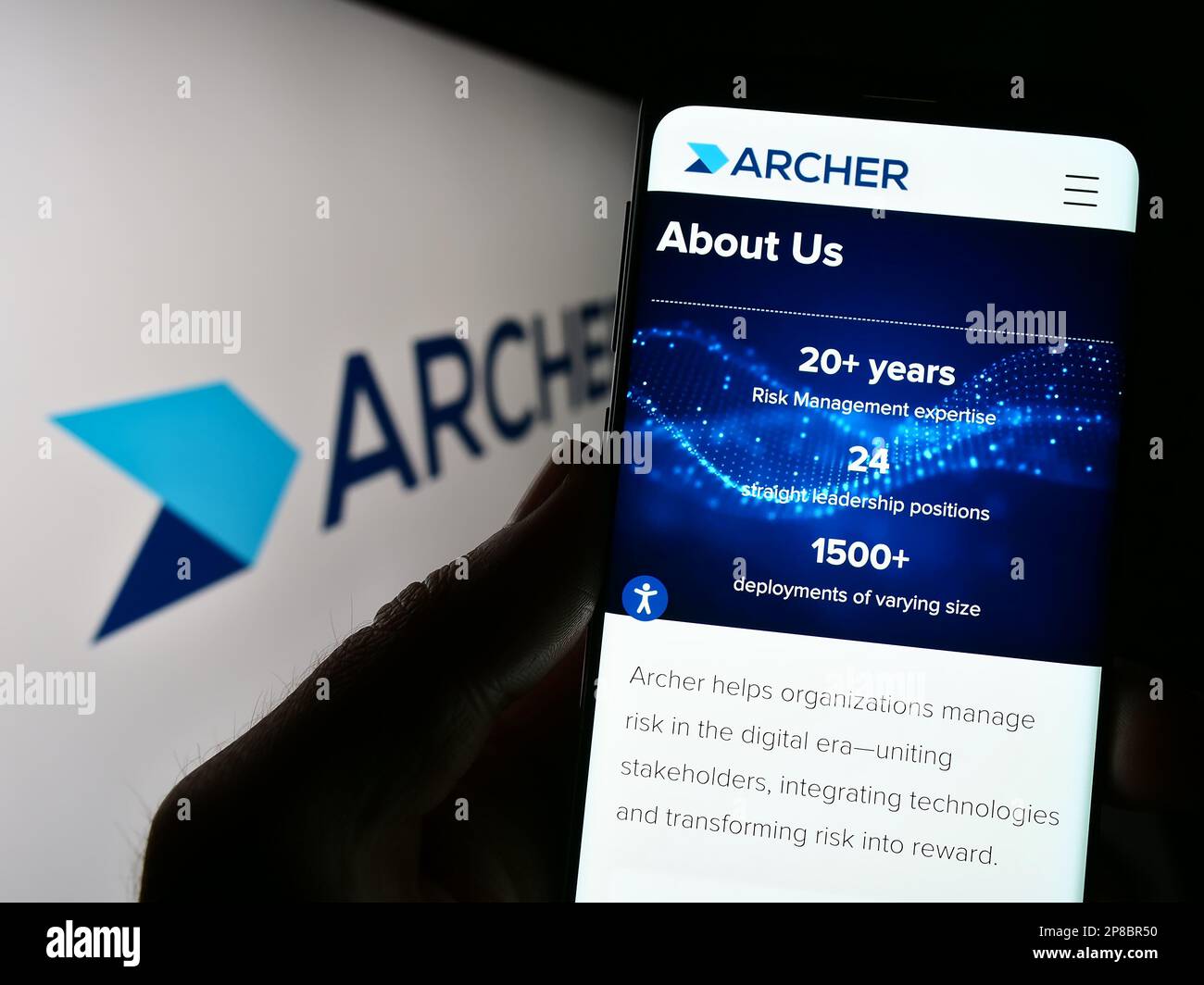 Personne tenant un téléphone portable avec une page Web du logiciel de gestion des risques Archer (RSA Security) à l'écran avec logo. Concentrez-vous sur le centre de l'écran du téléphone. Banque D'Images