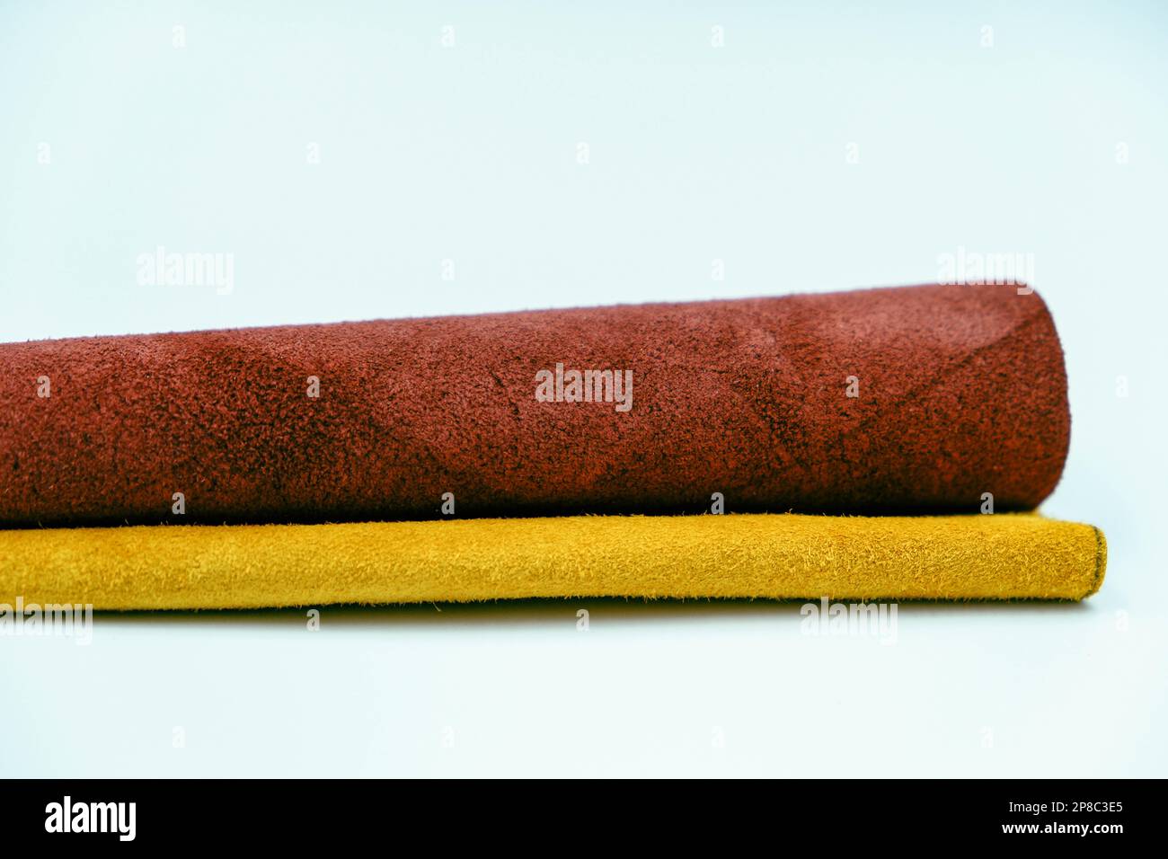 Pièces en cuir véritable isolées sur fond blanc. Rouleaux en cuir véritable jaune et rouge. Surface en cuir véritable. Matériel de loisirs et d'artisanat. Fabrication Banque D'Images