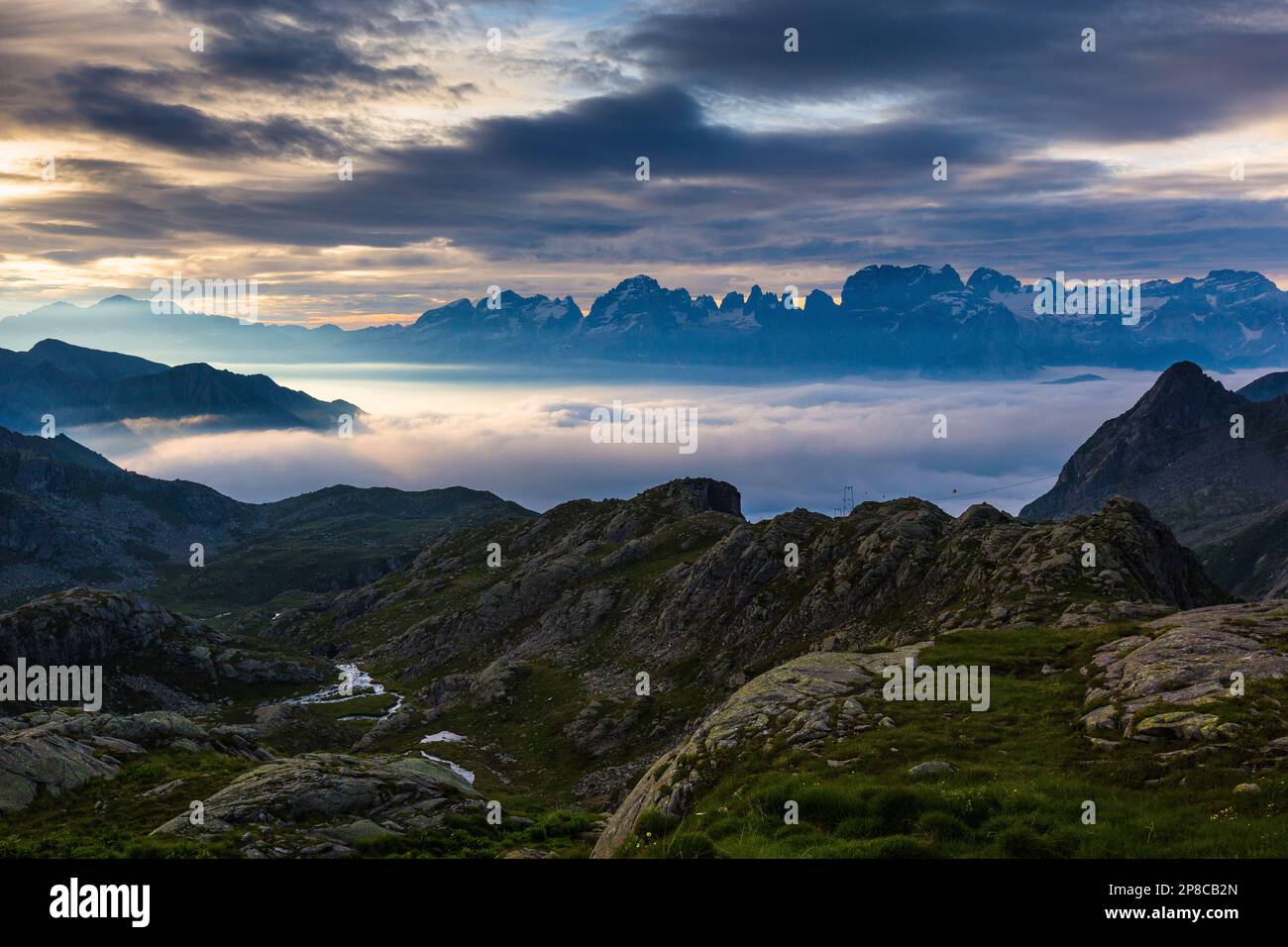 Lever du soleil avec marée de nuages au-dessus de la vallée de Campiglio. Vue depuis les rochers de Val d'Amola. En arrière-plan les profils des Dolomites de Brenta. Banque D'Images