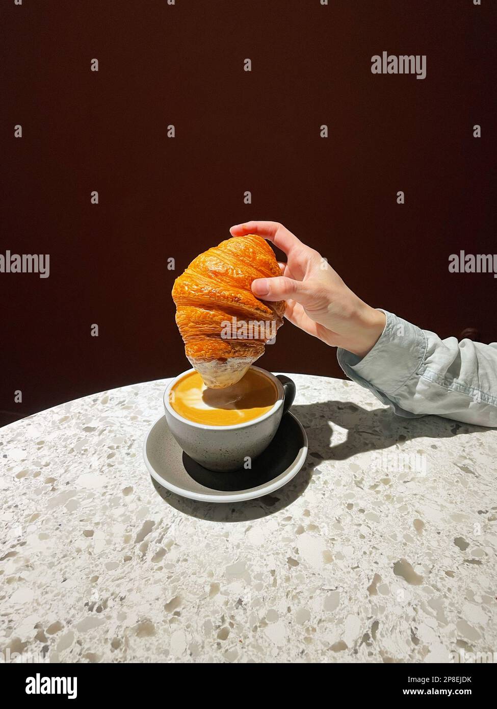 Gros plan d'une femme en train de tremper un croissant dans une tasse de café Banque D'Images